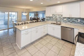 A modern kitchen with white cabinets, a granite countertop, and a stainless steel dishwasher. - Lovely canal-front home between bay & beach with private pool, dock, & AC (Virginia Beach)