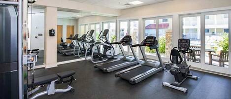 Une salle de sport équipée de tapis de course, d’un banc de développé couché et d’une machine de musculation.