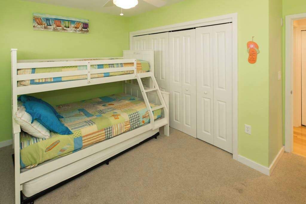 Una cama literera en una habitación con armario y puerta.
