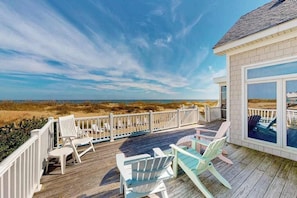 A wooden deck with outdoor seating, a white fence, and a view of the beach and ocean. - Fantastic oceanfront home w/private pool & hot tub, WiFi, central AC, & deck (Virginia Beach)