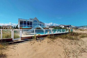 A beachfront property with a large house, a swimming pool, and a covered deck area. - Fantastic oceanfront home w/private pool & hot tub, WiFi, central AC, & deck (Virginia Beach)