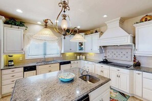 A kitchen with white cabinets, granite countertops, a central island, and pendant lighting. - Fantastic oceanfront home w/private pool & hot tub, WiFi, central AC, & deck (Virginia Beach)