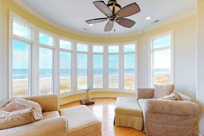 A room with a curved ceiling, large windows, a ceiling fan, and two beige sofas. - Amazing beachfront house w/private washer/dryer, WiFi, central AC, Ping-Pong (Virginia Beach)