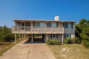A two-story building with a balcony on the upper floor, a covered walkway, and a small porch area. - Wonderful cottage w/Ping-Pong Table, WiFi, central AC, Deck - across from beach (Virginia Beach)