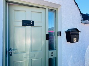 A door with a number 5 sign, a mailbox, and a window with a view.