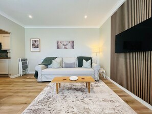 A living room with a sofa, coffee table, and artwork on the wall. - Nevis Nook near Fort William (Torlundy)