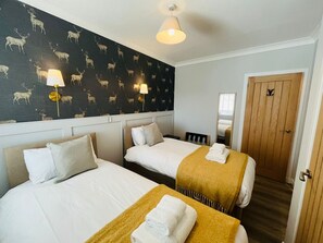 A hotel room with two beds, a dark patterned wall, and a wooden door. - Nevis Nook near Fort William (Torlundy)
