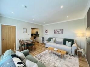 A living room with a sofa, a coffee table, and a dining area with chairs and a table.
