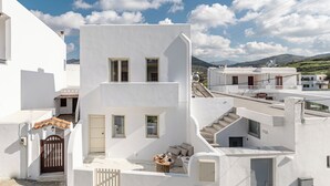 Un bâtiment blanc avec un escalier, une porte et un petit espace extérieur aménagé pour s’asseoir.