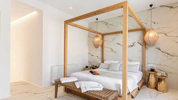 Une chambre à coucher moderne avec un lit à baldaquin, un banc en bois, un sol en marbre et des luminaires suspendus.