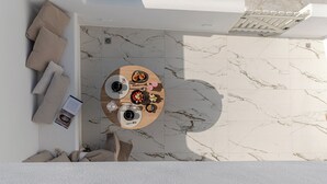 Vue plongeante d’une pièce avec une table ronde dressée pour deux personnes, un canapé et un plafond blanc.