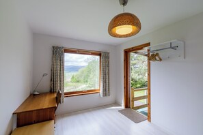 A room with a wooden desk, a large window with curtains, a hanging light fixture, and a door leading outside. - Tucked away cottage with fantastic views in the Cairngorms national park. (Inveruglass)