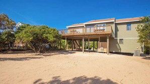 A beachfront property with a wooden deck, a covered outdoor area, and a sandy beach. - Hess affordable home w/easy walk to the beach, central AC, WiFi, & private W/D (Virginia Beach)