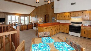 A spacious kitchen with wooden cabinets, a central island, and a dining area with a table set for four. - Hess affordable home w/easy walk to the beach, central AC, WiFi, & private W/D (Virginia Beach)