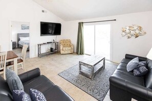 Ein Wohnzimmer mit einer Couch, einem Couchtisch, einem Fernseher und einem Sessel.