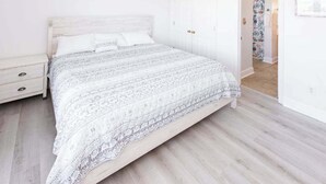 Una camera da letto con un letto, un comodino e una porta che dà su un'altra stanza.