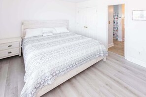 Ein Schlafzimmer mit einem Bett, einem Nachttisch und einer Tür zu einem anderen Raum.