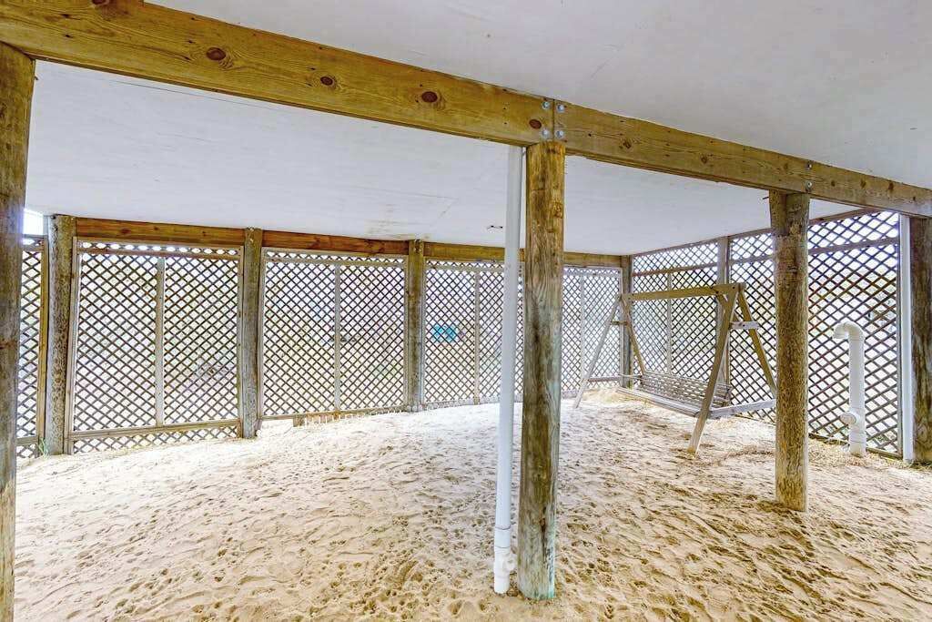 Espai interior amb sorra, bigues de fusta i tanca metàl·lica.