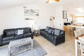 Ein Wohnzimmer mit zwei schwarzen Ledersofas, einem Couchtisch und einem Essbereich mit Tisch und Stühlen.