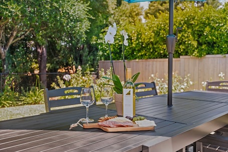 A table with a wine bottle, glasses, a cheese board, and a plant.