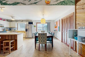 A spacious kitchen with modern appliances, a dining area with a chandelier, and a view of the outdoors. - Bright and comfortable home steps from beach w/private pool, WiFi, & central AC (Virginia Beach)