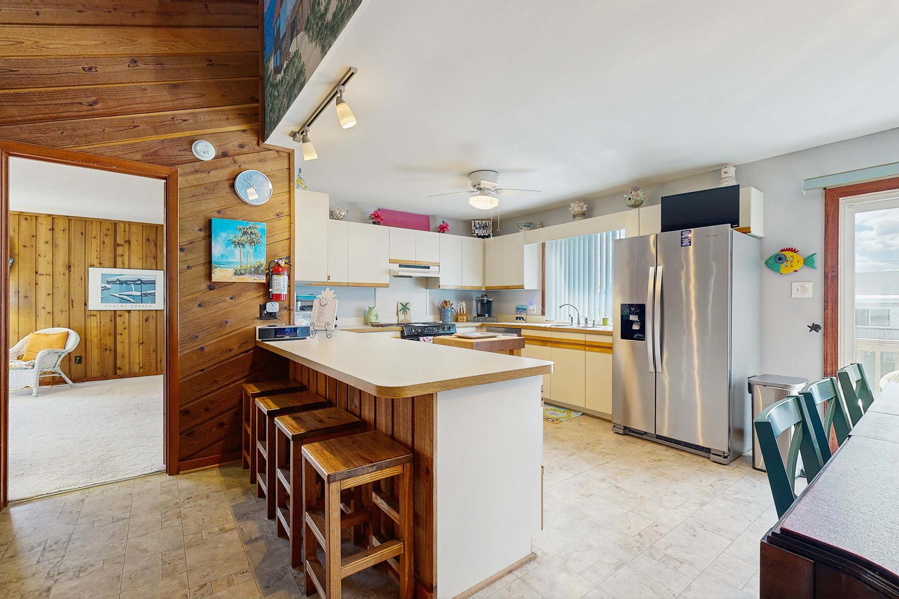 A modern kitchen with a wooden island, stainless steel appliances, and a dining area with green chairs.