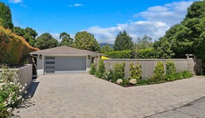 Eine Garage mit Wohnhof, befestigter Auffahrt, Holzzaun und verschiedenen Pflanzen.