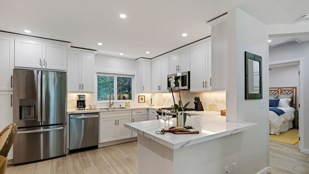 A modern kitchen with white cabinetry, stainless steel appliances, and a central island. - Coastal Palms - Walkable to Lower Village (Montecito)