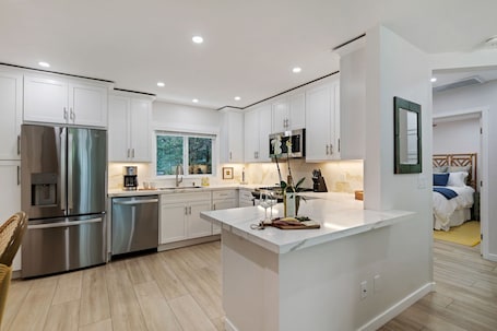 A modern kitchen with white cabinetry, stainless steel appliances, and a central island.