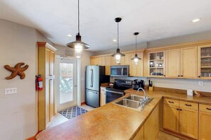 A modern kitchen with wooden cabinets, stainless steel appliances, pendant lighting, and a built-in oven. - Dog-friendly home w/private pool and washer/dryer, WiFi, central AC, patio, deck (Virginia Beach)