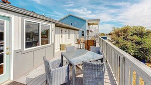 En täckt uteplats med möbler i rotting, en matplats och utsikt över havet.