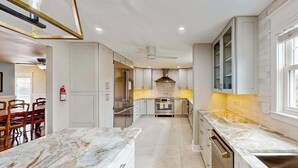 Una cocina moderna con armarios blancos, encimera de mármol y una isla central.