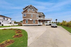 A two-story house with a balcony, a driveway, and a lawn.