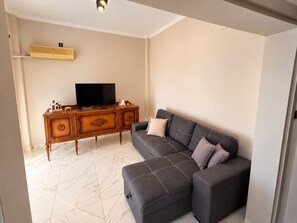 Una sala de estar con un sofá modular, un televisor de pantalla plana y un mueble de madera.