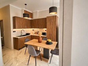 Una cocina moderna con armarios de madera, encimera de mármol y una mesa de comedor con sillas.