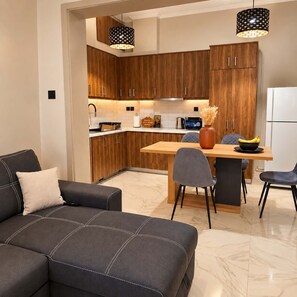 A modern kitchen with wooden cabinets, a dining table, and a sofa. - Nea Ionia Urban Nest – Fotis’ Athens Getaway (Nea Ionia)