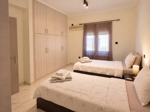 Ett hotellrum med två sängar, en garderob, ett fönster med gardiner och en sänglampa.