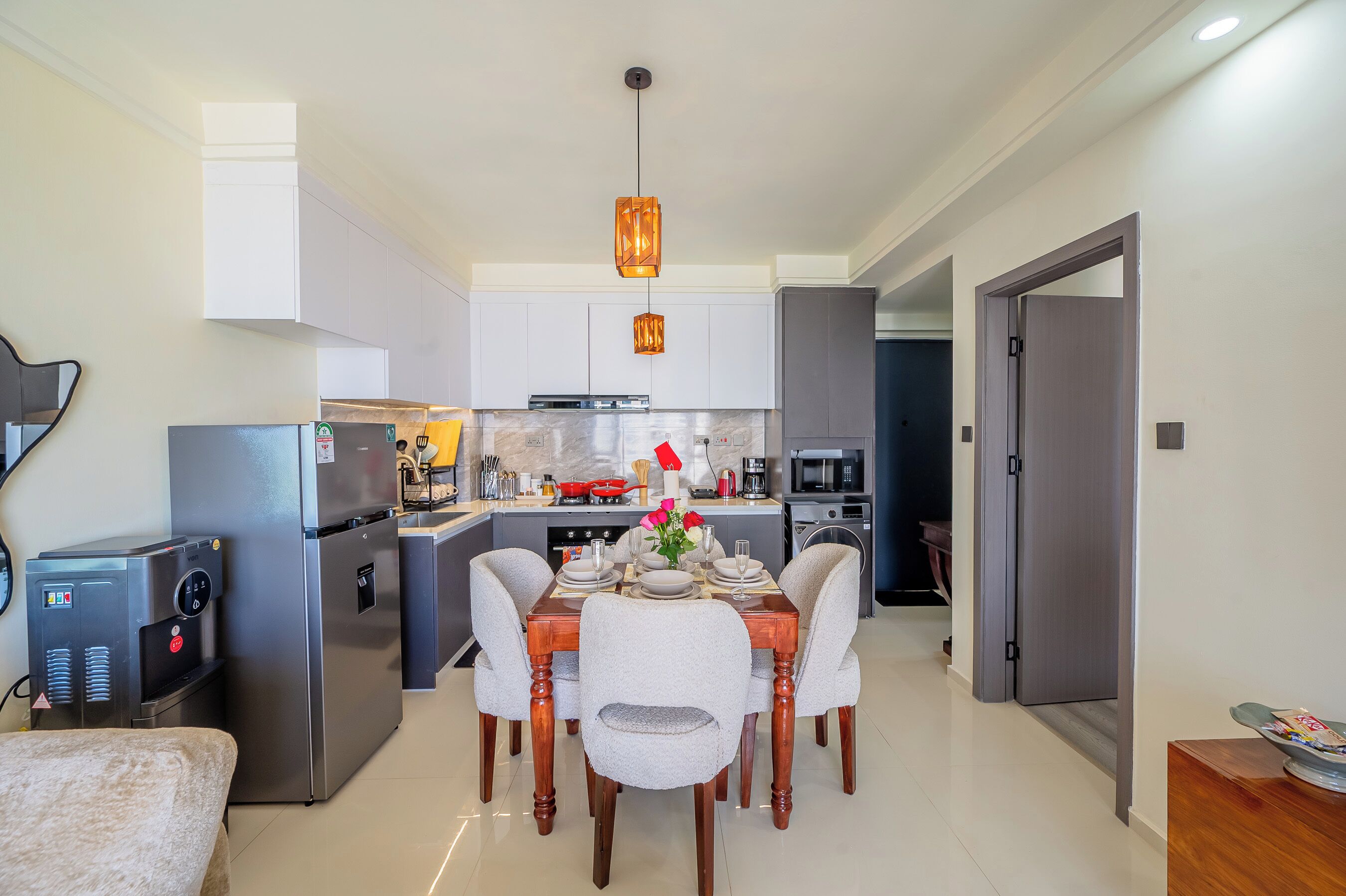 A modern kitchen with a dining area, stainless steel appliances, and a water dispenser.