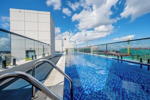 A rooftop infinity pool with a clear view of the city skyline, a glass railing, and a modern building facade. - Misty Springs 1BR near GTC - Heated Infinity Pool, Gym, Fast WiFi (Nairobi)