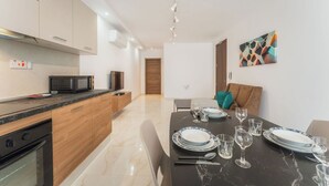 Un comedor moderno con una mesa de mármol, paredes blancas y un mueble de madera.
