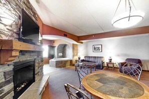 A living room with a stone fireplace, a round table, and two sofas.