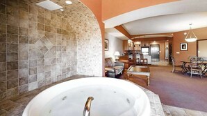 Ett spaområde med ett bubbelbad, en öppen spis och ett vardagsrum med en soffa och ett matbord.