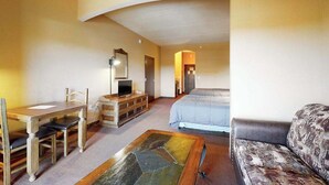 Ett hotellrum med en säng, en soffa, ett skrivbord med en stol, en tv och en spegel.