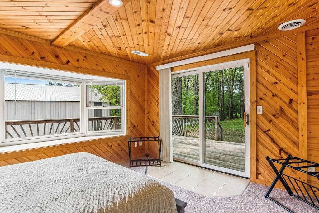 Une pièce de style cabane en bois, comprenant un lit, un banc et une porte-fenêtre coulissante donnant sur une terrasse extérieure.