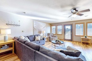 A modern living room with a sectional sofa, a round coffee table, and a ceiling fan.