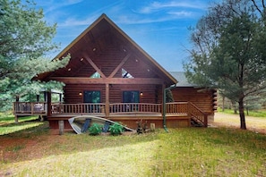 Eine Blockhütte mit Veranda, einer überdachten Terrasse und einem kleinen Boot im Vordergrund.