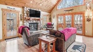 Un intérieur chaleureux et accueillant, avec une cheminée en pierre, des meubles en bois et un grand téléviseur.