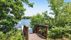 Un pont en bois menant à une étendue d’eau, entouré d’une végétation luxuriante.