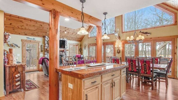 Une cuisine spacieuse avec des poutres en bois, un grand îlot central et un coin repas doté de chaises en bois.