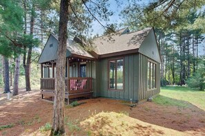A cabin with a porch, large windows, and a wooded setting. - Cozy Home in the trees, w/ large yard, fire pit, gas grill, & WIFI (Friendship)